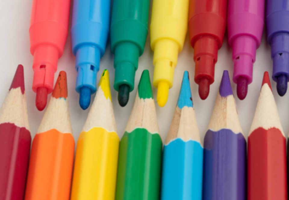 Close-up of colourful markers and matching coloured pencils arranged in two neat rows, showcasing vibrant shades including red, pink, blue, green, yellow, orange, purple, and dark blue.